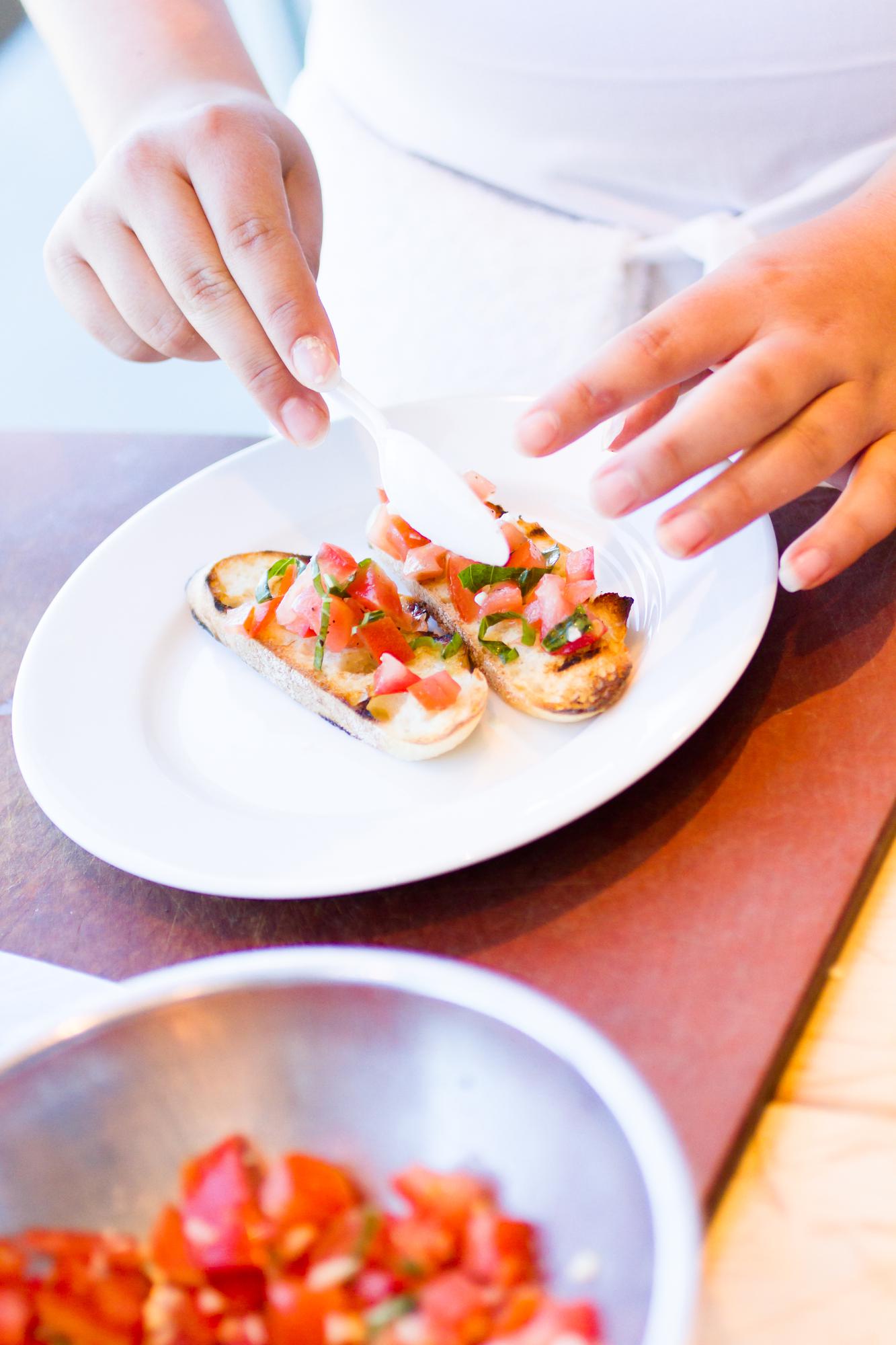 close-up of hands plating a dish in a warm kitchen